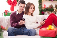 Paar auf Sofa mit Geschenken und Smartphones