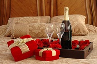 Hotelzimmer-Bett mit romantischer Dekoration und Sektflasche