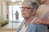 Seniorin im Pflegeheim mit Enkelkind im Hintergrund