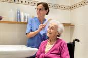Altenpflegerin kämmt Seniorin im Bad die Haare.