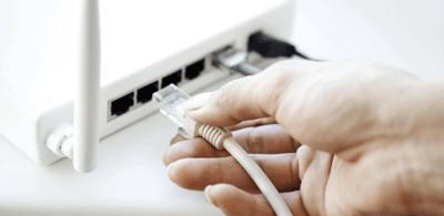Person steckt LAN-Kabel in den Glasfaser-Router