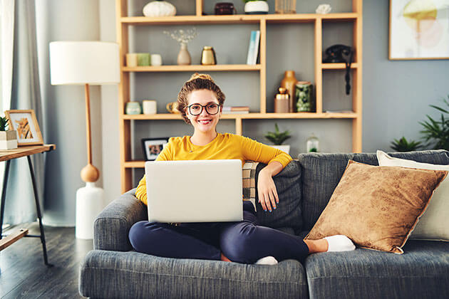 Junge Frau mit Laptop auf einem Sofa