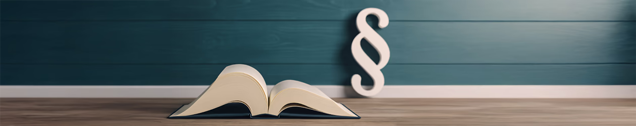 Buch mit Paragraphen-Zeichen im Hintergrund