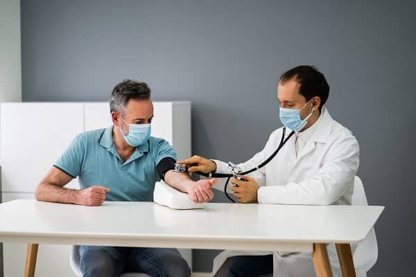 Leistungsfall BU: Arzt misst Blutdruck bei einem Patienten