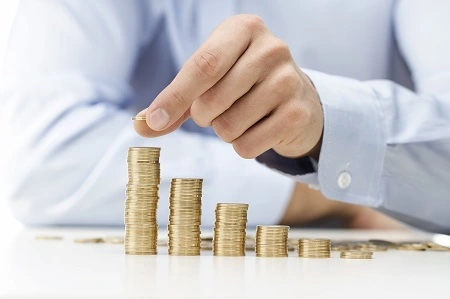 Ein Mann stapelt Münzen bei der Berechnung der Rentenhöhe.