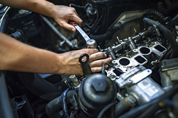 Erwerbsunfähigkeitsversicherung: Mechaniker arbeitet mit Ratschenschlüssel an einem Motor