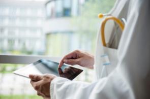 Arzt mit Stethoskop hält Tablet in der Hand