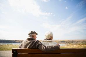 Senioren sitzen auf einer Bank und blicken in die Ferne.