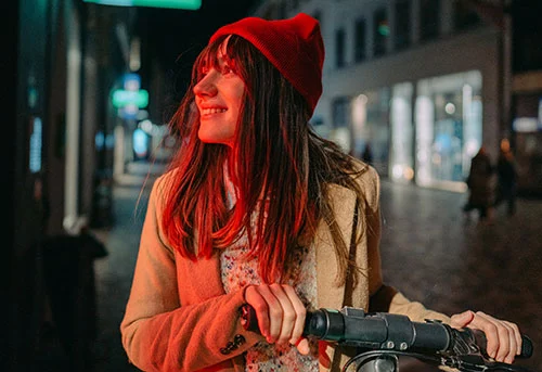 Eine junge Frau ist nachts mit ihrem E-Scooter in der Fußgängerzone unterwegs.