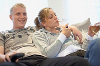 Mann und Frau sitzen in ihrer Wohnung auf dem Sofa. Sie zündet sich genüsslich eine Zigarette an.