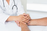 Ärztin hält Hand eines Patienten