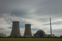 Atomkraftwerk neben Kühltürmen vor Himmel voller Wolken