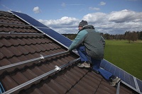 Ein Mann montiert eine Solaranlage auf einem Hausdach.