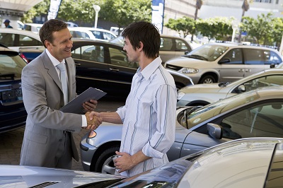 Autohändler und Käufer schließen einen Kaufvertrag.