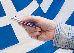 Mann zahlt per Kreditkarte vor griechischer Flagge