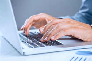 Laptop mit tippenden Händen auf der Tastatur