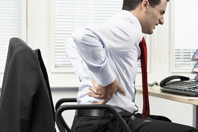 Angestellter im Büro mit Rückenschmerzen