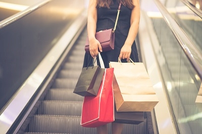 Konsumklima: Frau mit Einkaufstüten auf Rolltreppe