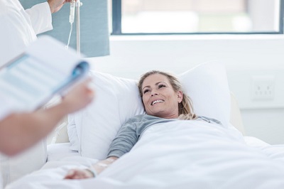 Frau im Krankenhausbett bei Visite