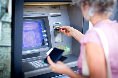 Eine Frau steht am Geldautomat. Beim Skimming werden ihre Daten vom Magnetstreifen geklaut. Foto: JAG IMAGES/Getty Images