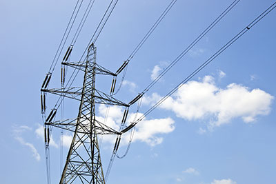 Ein Strommast von unten fotografiert vor blauem Himmel