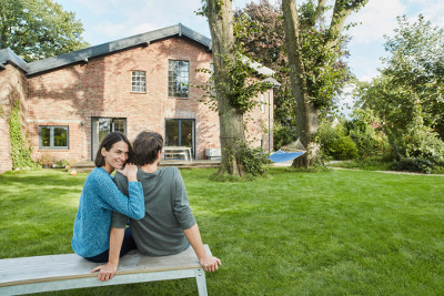 Ein Paar sitzt vor einem Haus. Foto: Westend61/Gettyimages