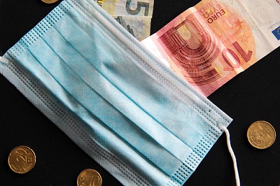 Schutzmaske mit Münzen und Geldscheinen in Euro.