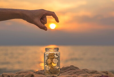 Geldanlage im Ausland zu guten Festgeldzinsen - Münzen in Glas vor Sonnenuntergang