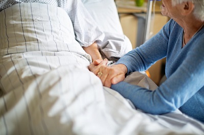 Ältere Frau am Krankenhausbett ihres Mannes.