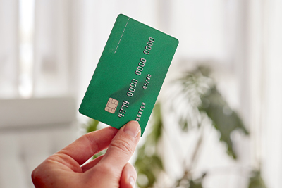 Eine Hand hält eine grüne Kreditkarte in die Luft