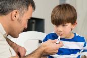 Vater und krankes Kind mit Fieberthermometer