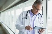 Ein Arzt im Krankenhaus schaut auf ein Tablet.