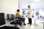 Patientin mit Arzt im Wartezimmer einer Praxis