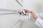 Hände einer Apothekerin holen Medikament aus Schublade