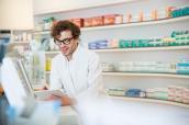 Apotheker an der Kasse mit Medikamenten im Hintergrund