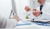 Arzt reicht Patient ein Medikamtent.