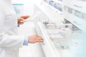 Apothekerin sucht mit Rezept in der Hand nach Medikament.