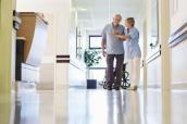Krankenschwester hilft älterem Patienten auf dem Krankenhausflur.