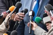 Journalisten halten Mikrofone bei einem Interview
