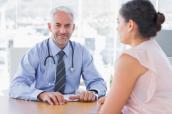 Ein Arzt lächelt während er mit einer Patientin spricht.