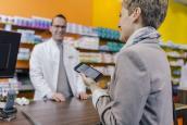 Frau in Apotheke an der Theke mit Handy
