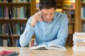 Ein Student sitzt in einer Bibliothek und liest.