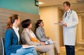 Patientinnen mit Arzt im Wartebereich einer Praxis
