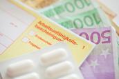 Arbeitsunfähigkeitsbescheinigung und Tablettenpackung liegen auf Geldscheinen