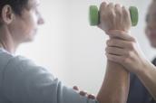 Patient bei einer Physiotherapie mit Hantel in der Hand