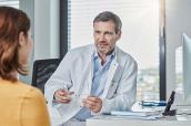 Arzt im Gespräch mit einer Patientin im Sprechzimmer