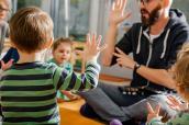 Kinder mit einem Erzieher im Kindergarten