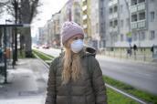 Frau mit Maske an einer Trambahn-Haltestelle in Berlin