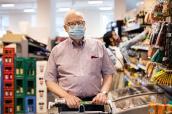 Älterer Mann mit Maske und Einkaufswagen in einem Berliner Supermarkt.