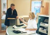 Patient beim Arzt am Empfangstresen (DAK Gesundheit)
